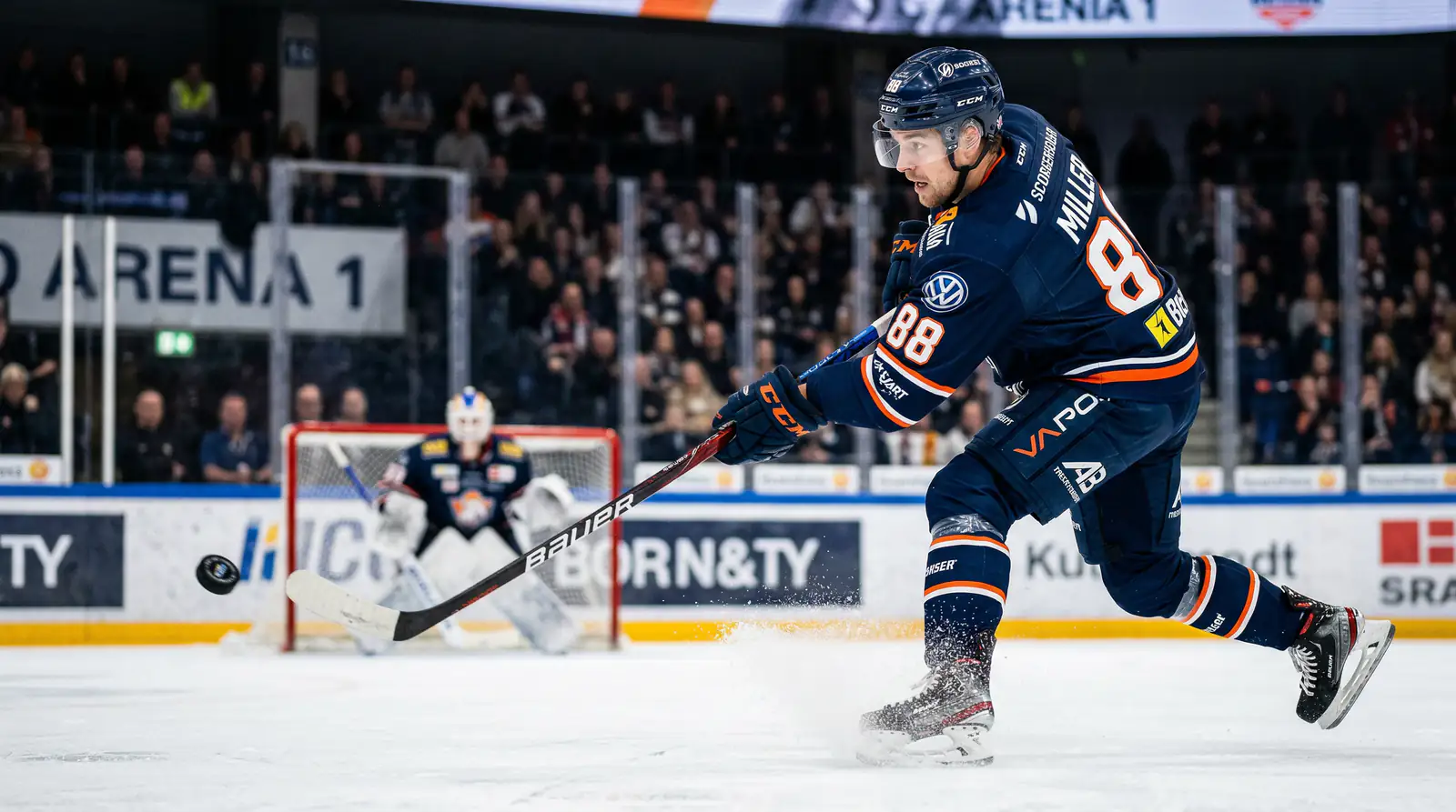 Eishockeyspieler schießt den Puck mit voller Kraft aufs Tor unter Flutlicht