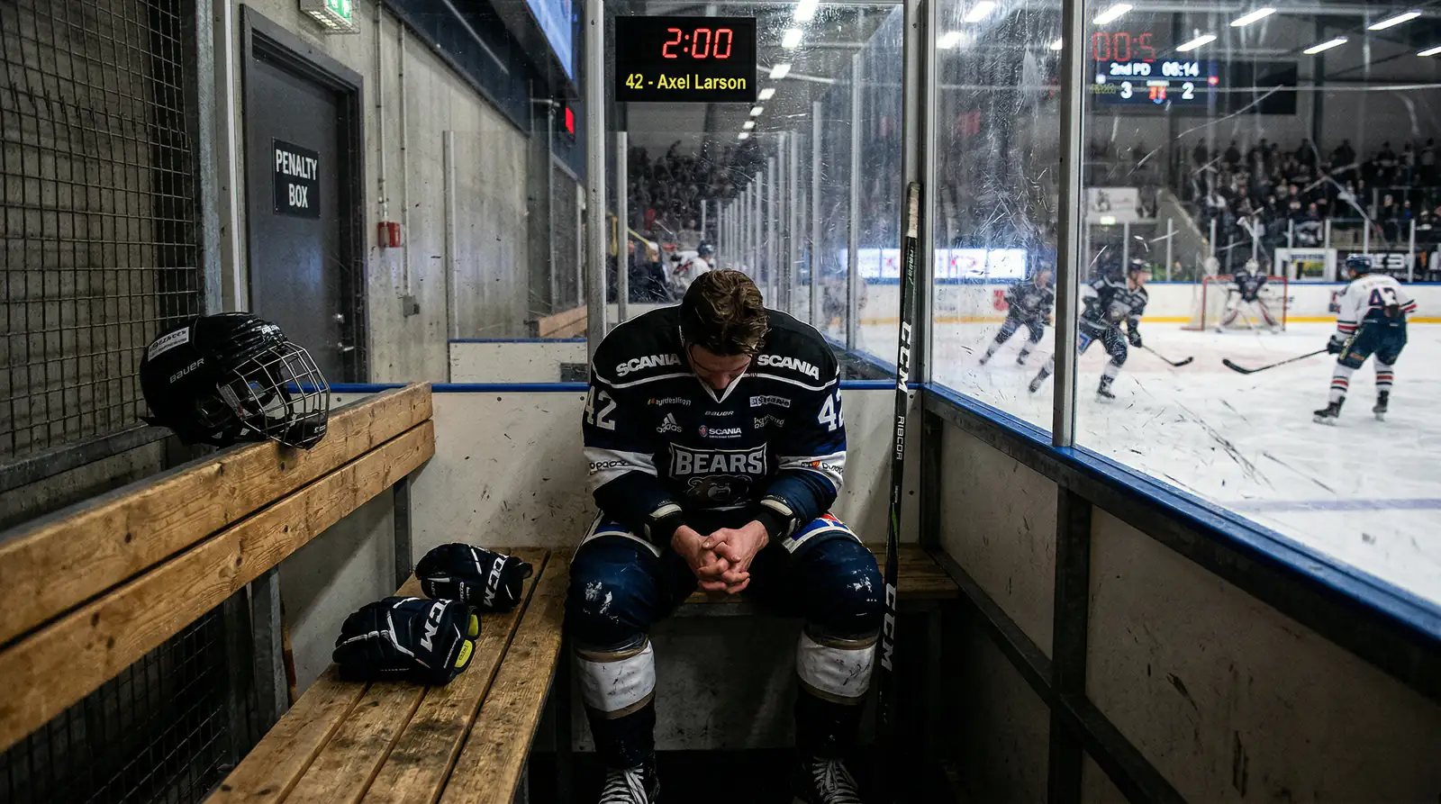 Eishockeyspieler sitzt frustriert auf der Strafbank mit gesenktem Kopf