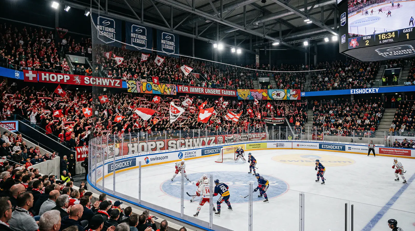 Ausverkauftes Schweizer Eishockeystadion mit begeisterten Fans und Spielern auf dem Eis